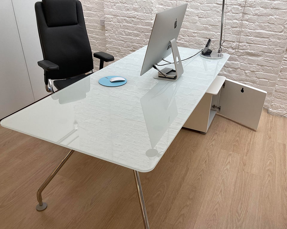 Prospero White glass designer desks for executives or home offices with white glass desk tops and matt white lacquered structural storage and chrome legs. shown here with matching round glass table and a high back leather executive chair with height adjustable arms
