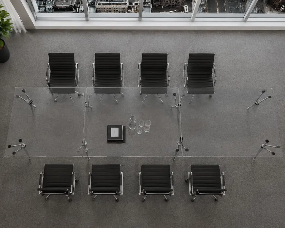 luxury glass conference table with eight black boardroom chairs around it